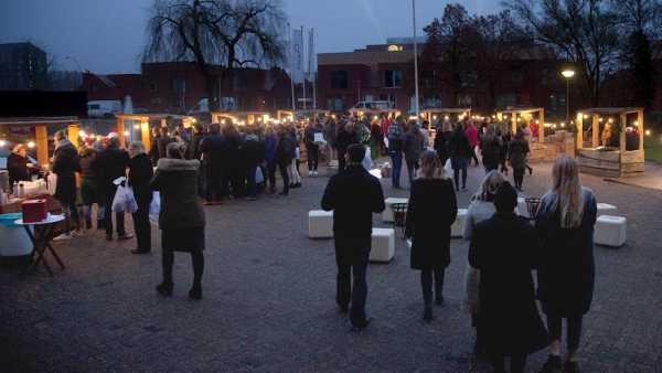 Groot plein met een kerstmarkt met verlichte kramen