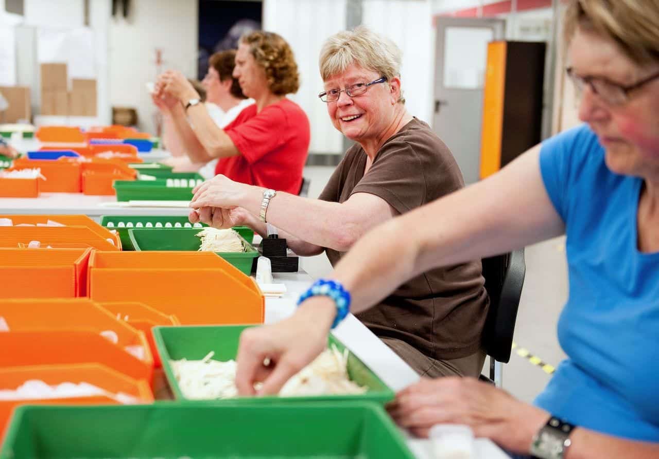 Personen die pakketjes aan het maken zijn bij een sociale werkplaats.