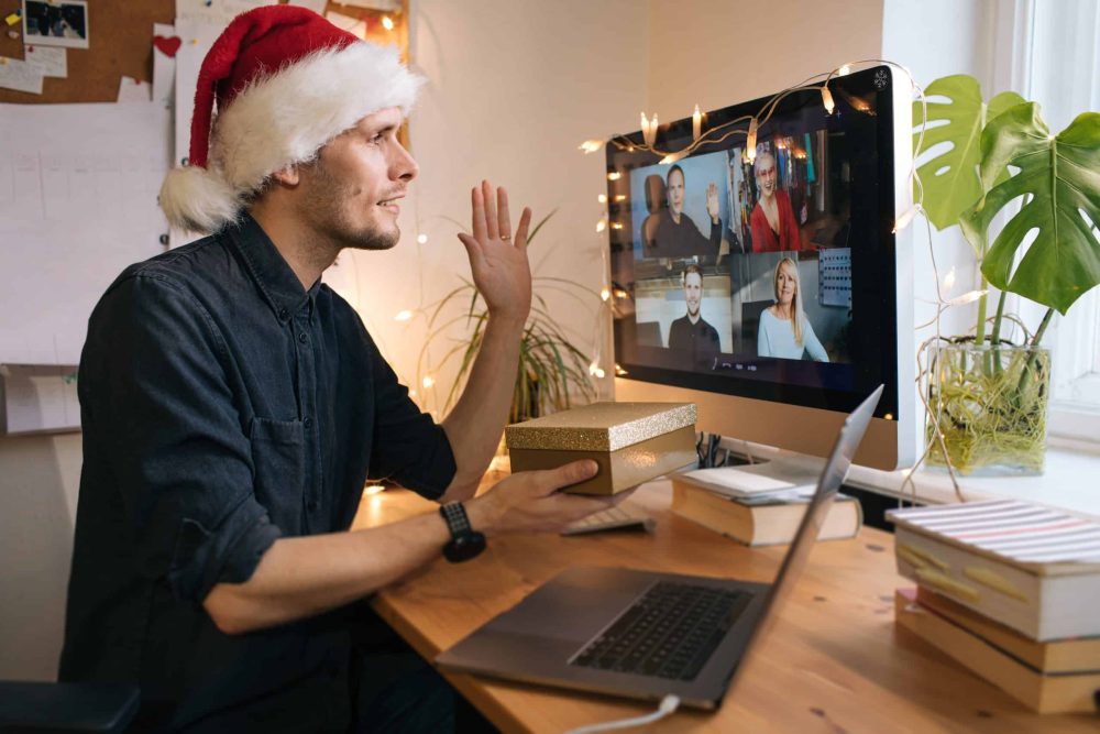 Man in een online meeting met zijn collega's om de kerstgeschenken uit te pakken.